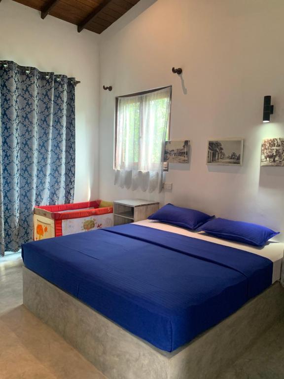 a bedroom with a bed with blue sheets and a window at Villa Unawatuna in Unawatuna