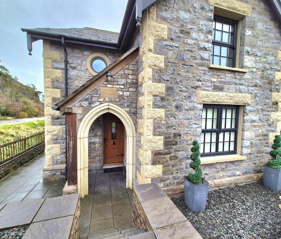 een stenen huis met een deur en een binnenplaats bij Winster Cottage, Meathop, Grange-Over-Sands in Grange Over Sands