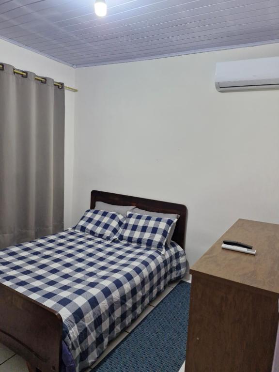 a bedroom with a bed with a blue and white checkered blanket at House - Cantinho de Jacaré in Jacarèzinho