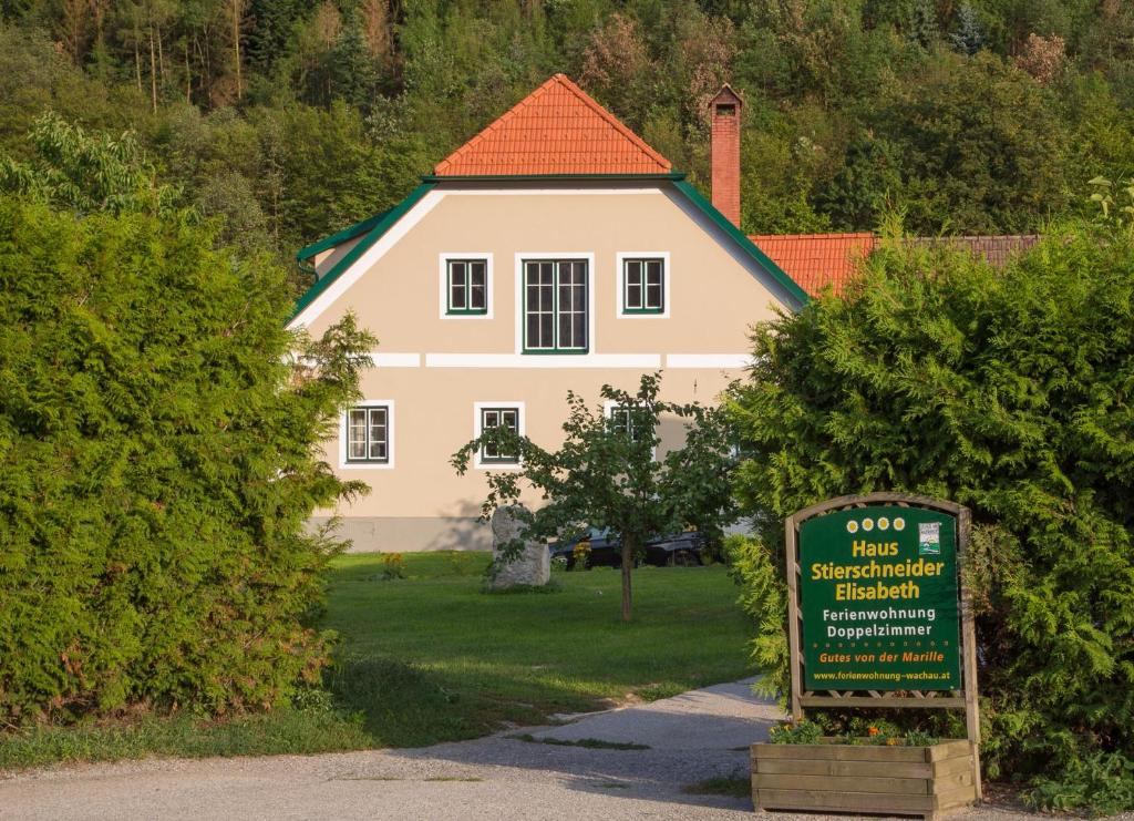 une maison blanche avec un panneau devant dans l'établissement Ferienwohnungen Haus Stierschneider, à Spitz