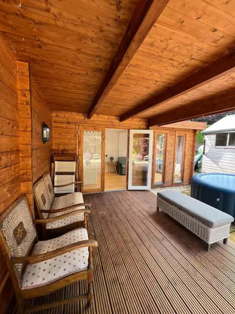 porche de una cabaña con cama y sillas en Lodge near Bath for relaxing getaway with Hot tub, en Chittoe