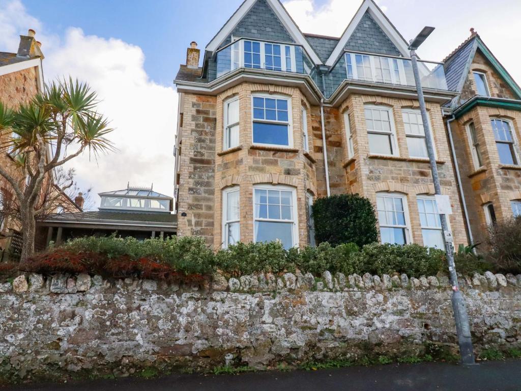 a large brick house with a stone wall at Tradewinds in Newquay