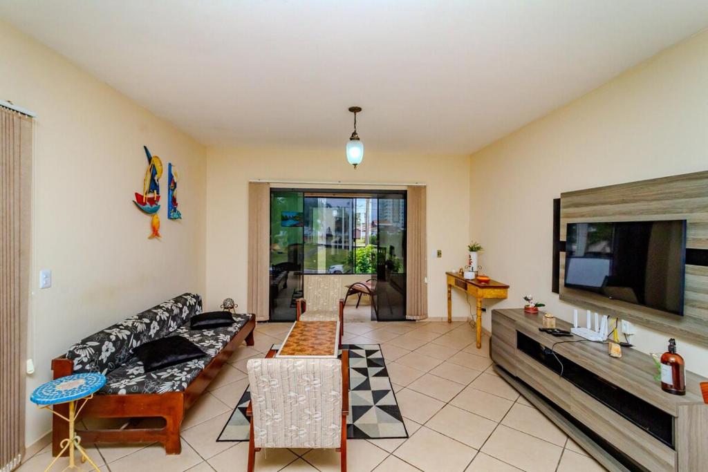 a living room with a couch and a flat screen tv at Beira Mar e Frente Lagoa de Barra Velha 4 Quartos in Barra Velha