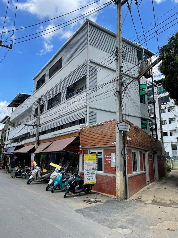 a white building with motorcycles parked in front of it at Banhor Residence in Chiang Mai