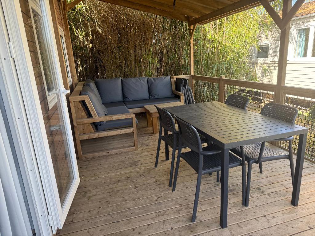 a porch with a table and chairs and a couch at Mobil-home 33 st jean de monts camping 5 étoiles in Saint-Jean-de-Monts