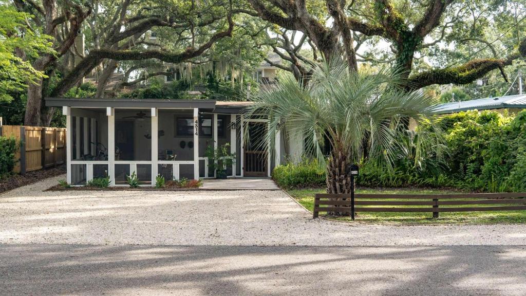 een wit huis met een palmboom en een hek bij The Shipwright's Bungalow in Saint Simons Island