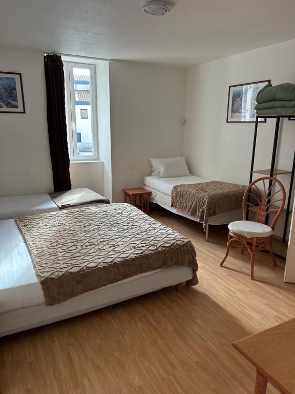 a bedroom with two beds and a table and a chair at Hotel Du Rocher in Le Caylar