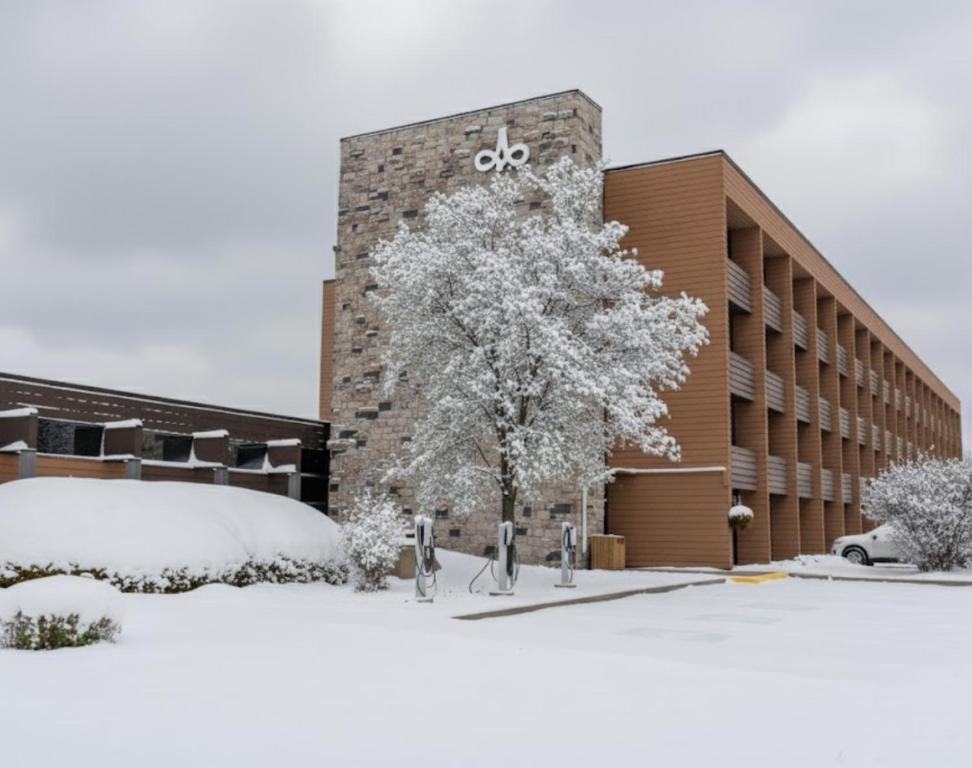 a snow covered building with a tree in front of it at Hôtels Gouverneur Sept-Îles in Sept-Îles