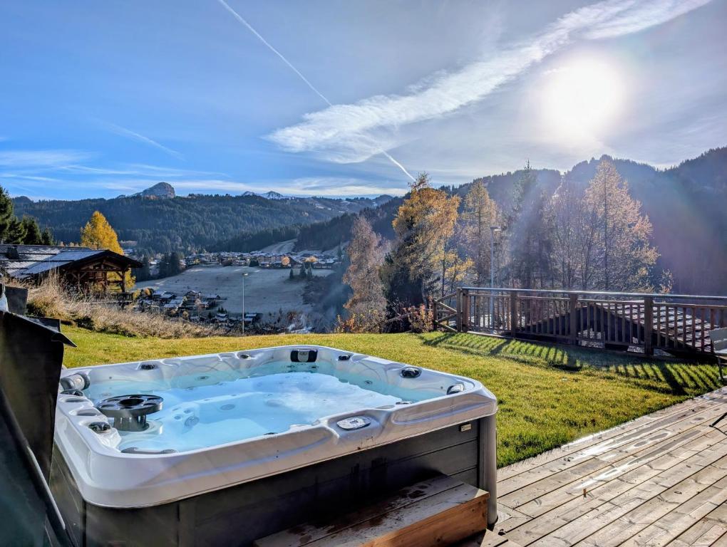a hot tub on a deck with a view of a mountain at Chalet Camomille in Les Gets