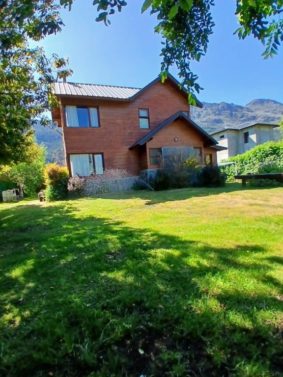 a house with mountains in the background at Cabañas Peñi Huen in Lago Puelo