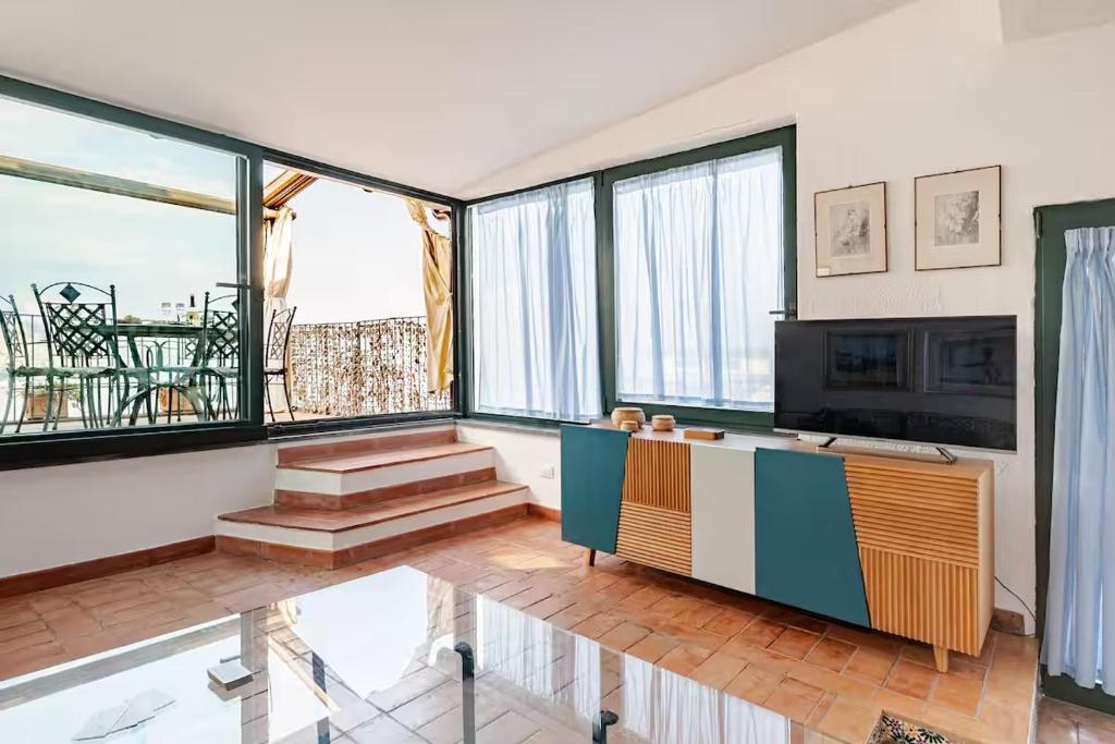 een woonkamer met grote ramen en een televisie bij DIMORA DISIU - Jacuzzi & Sea View - 4 minuti a piedi dal centro in Taormina