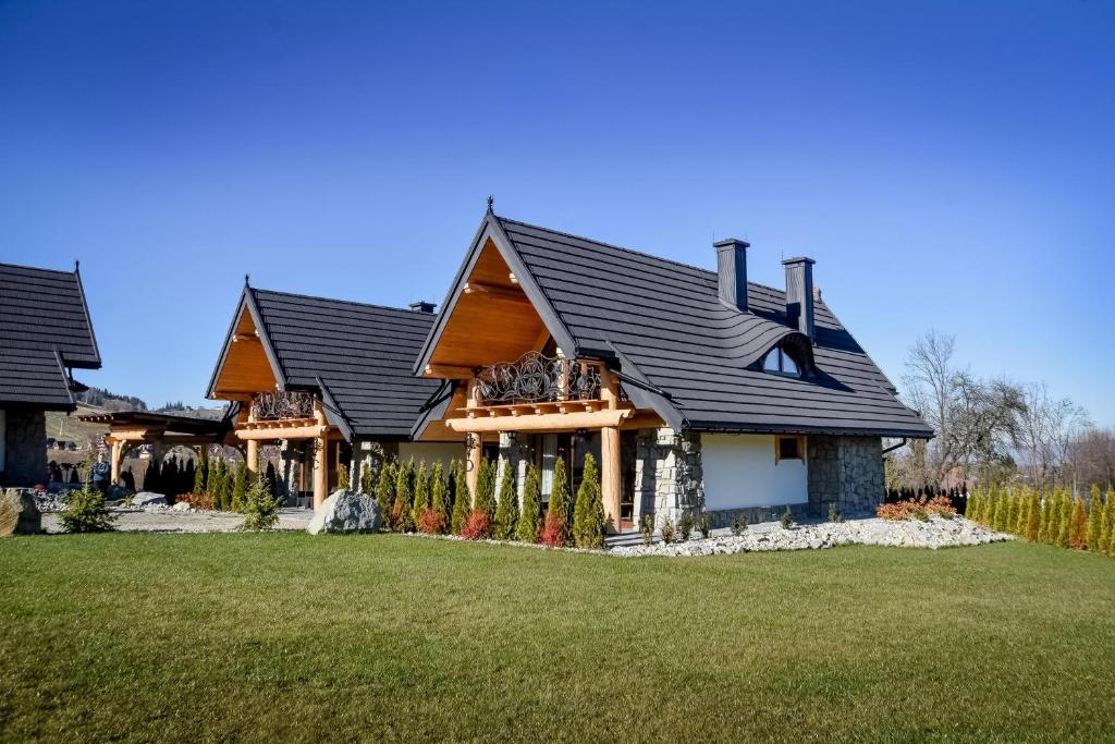 a house with a black roof and a yard at Zbójeckie Sioło in Bukowina Tatrzańska