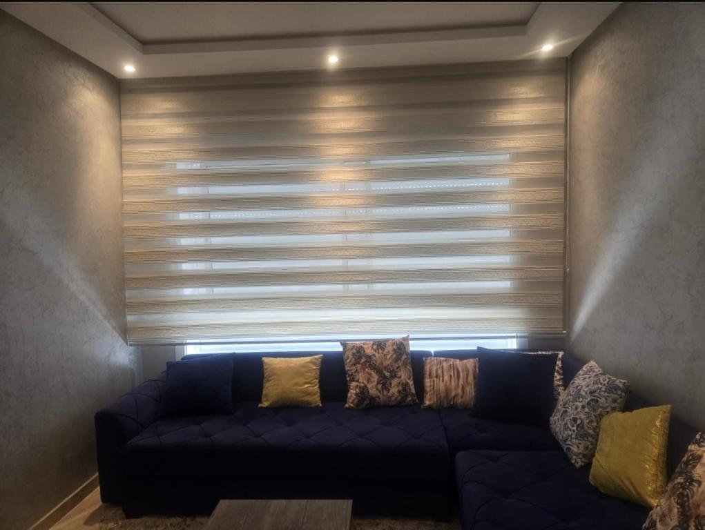 a blue couch in a room with a window with blinds at Residence kettani in Bouznika