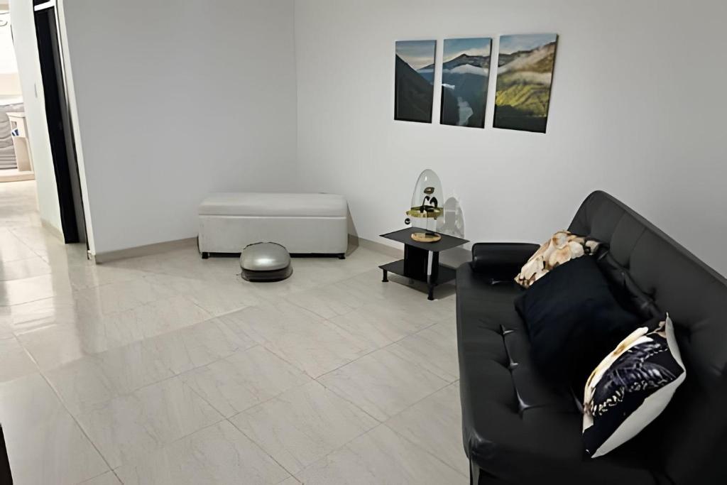 a living room with a black couch and a table at Espacioso y Elegante en Milán in Manizales