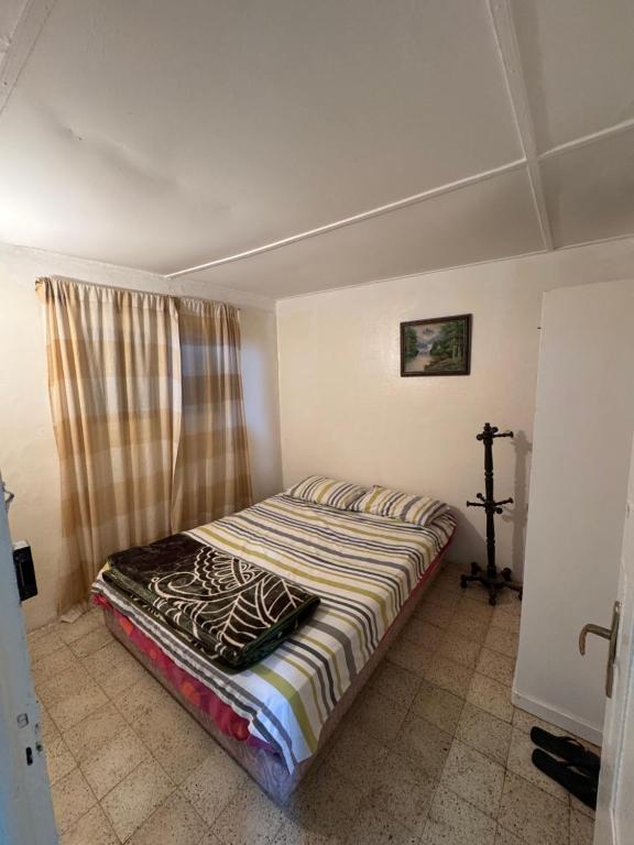 a bedroom with a bed with a striped comforter at Cabanon pied sur mer in Mohammedia