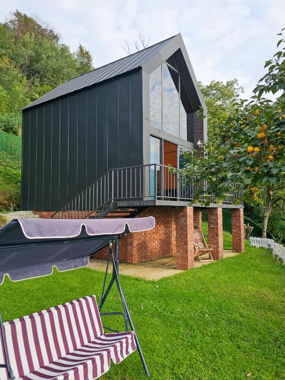 a house with a balcony and a chair in the yard at Green Hill in Batumi