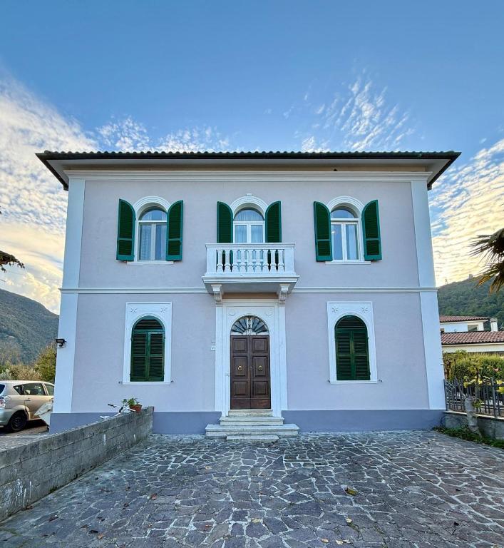 a white house with green windows and a balcony at Grand Tour - Cascata delle Marmore in Le Marmore