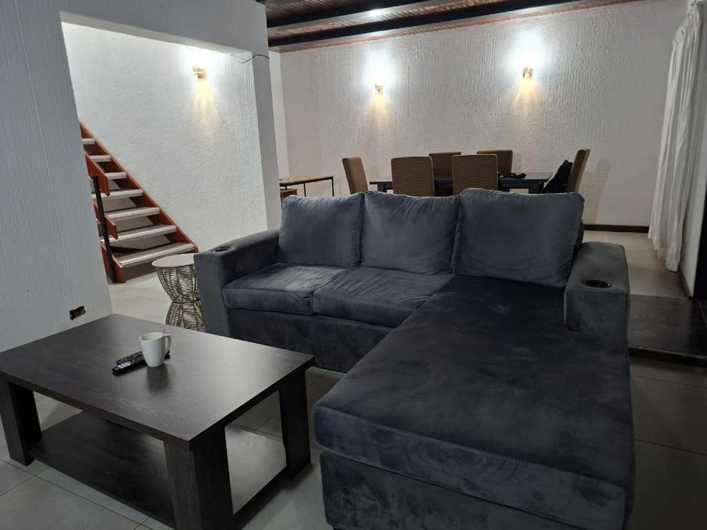 a living room with a blue couch and a table at Golf Course Apartment in Maseru