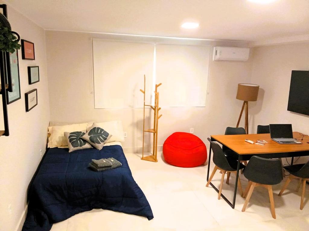 1 dormitorio con cama y mesa con ordenador portátil en Hospedagem e Coworking - suítes, en Anápolis