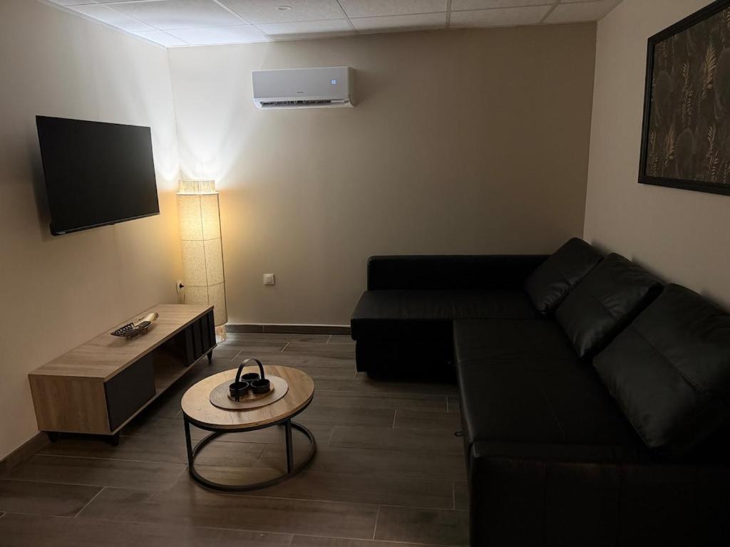 Una sala de estar con un sofá negro y una mesa. en chez isabelle et thierry, en Harnes