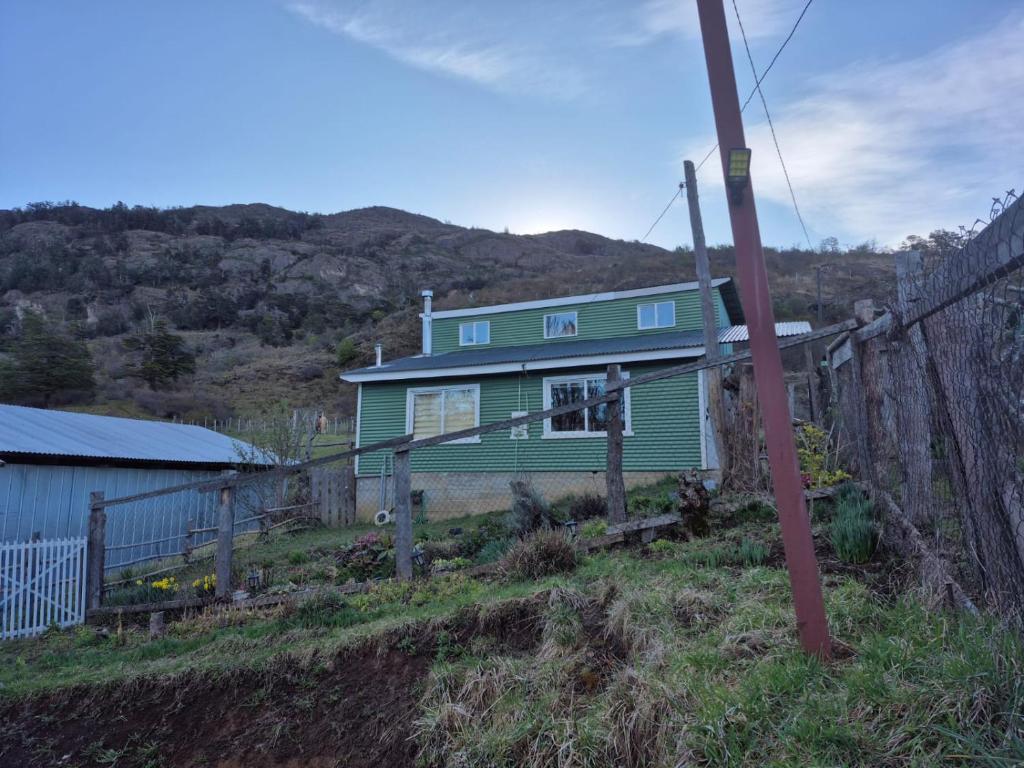 una casa verde en la cima de una colina en Cabaña el Sauco, en Puerto Guadal