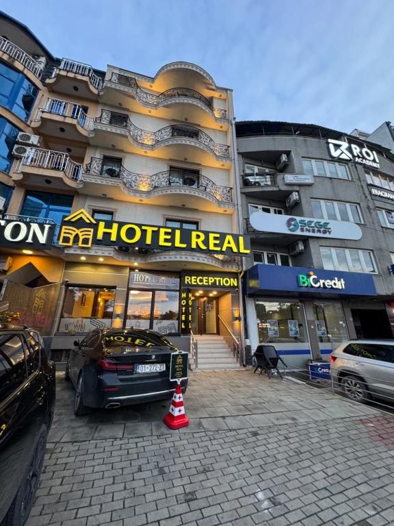 um prédio de hotel com um carro estacionado na frente em Hotel Real em Pristina