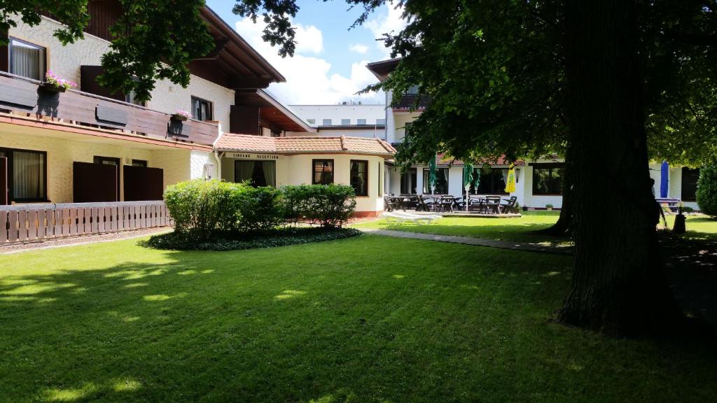 ein grüner Hof mit einem Baum und einem Gebäude in der Unterkunft Hotel Büchner Garni in Bad König