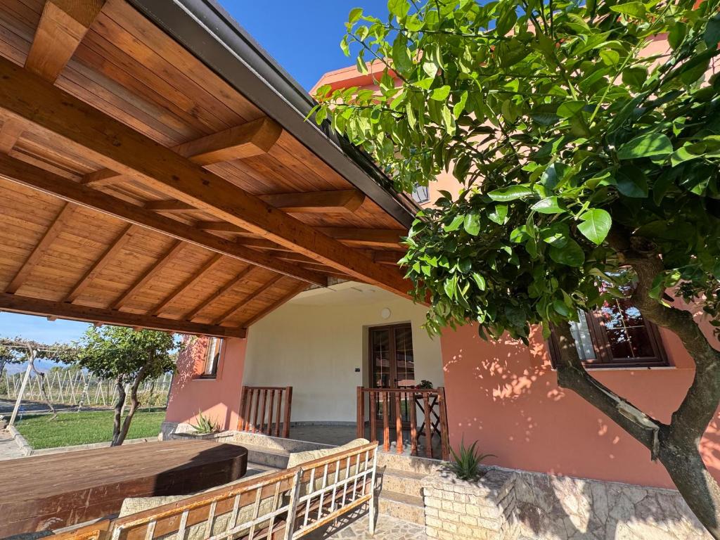 a wooden pergola on a house with a tree at Bujtina Tushaj in Lezhë