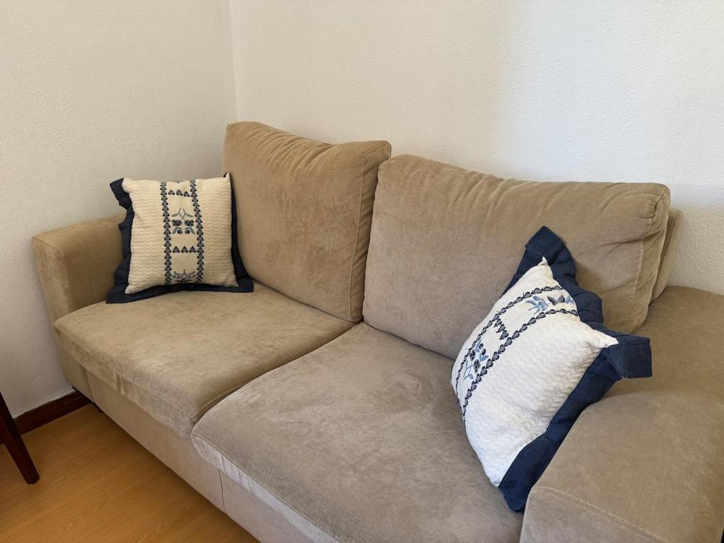 a brown couch with two pillows on it at Family & Pet Friendly Beach Stay & Fast Wi-Fi in Figueira da Foz