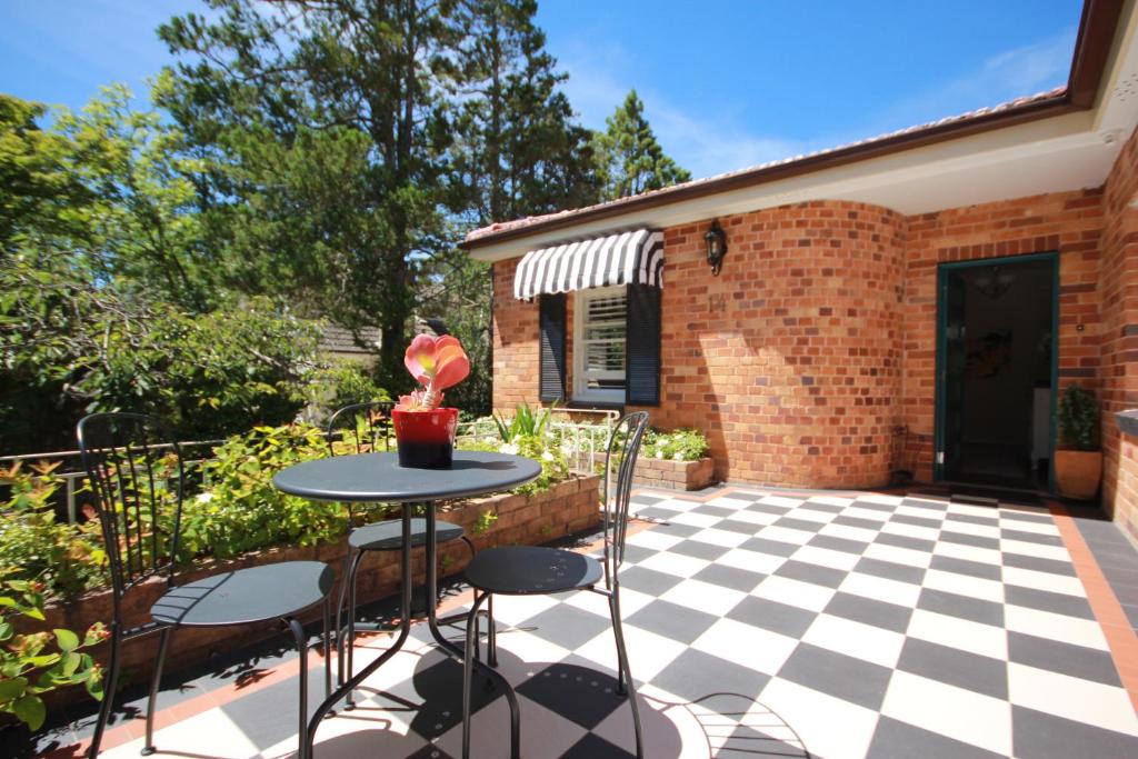 un patio con mesa y sillas en un suelo a cuadros en Winston Cottage at Three Sisters, en Katoomba