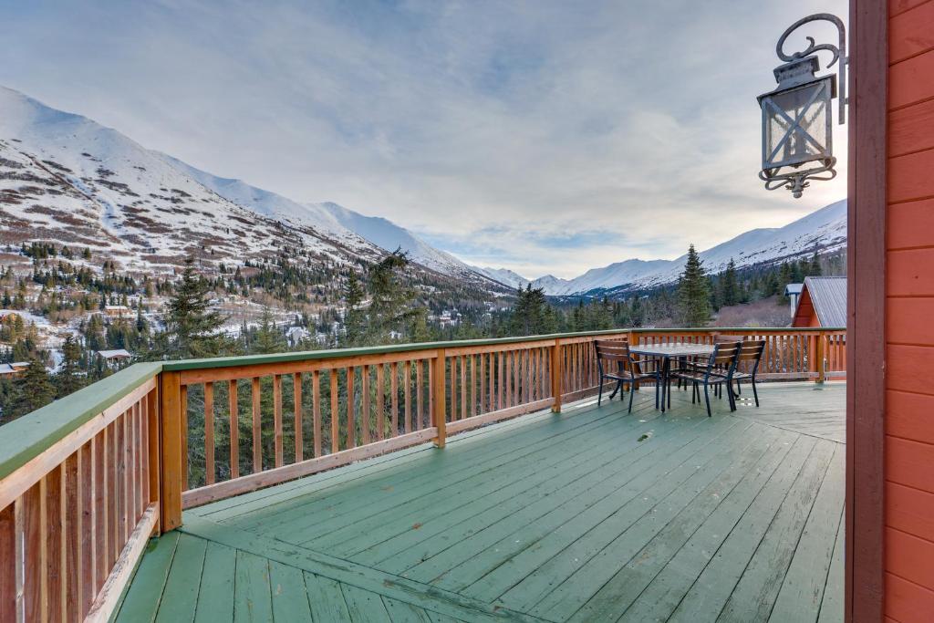 a wooden deck with a table and chairs on it at Stunning Alaskan Getaway with River and Mtn Views in Eagle River
