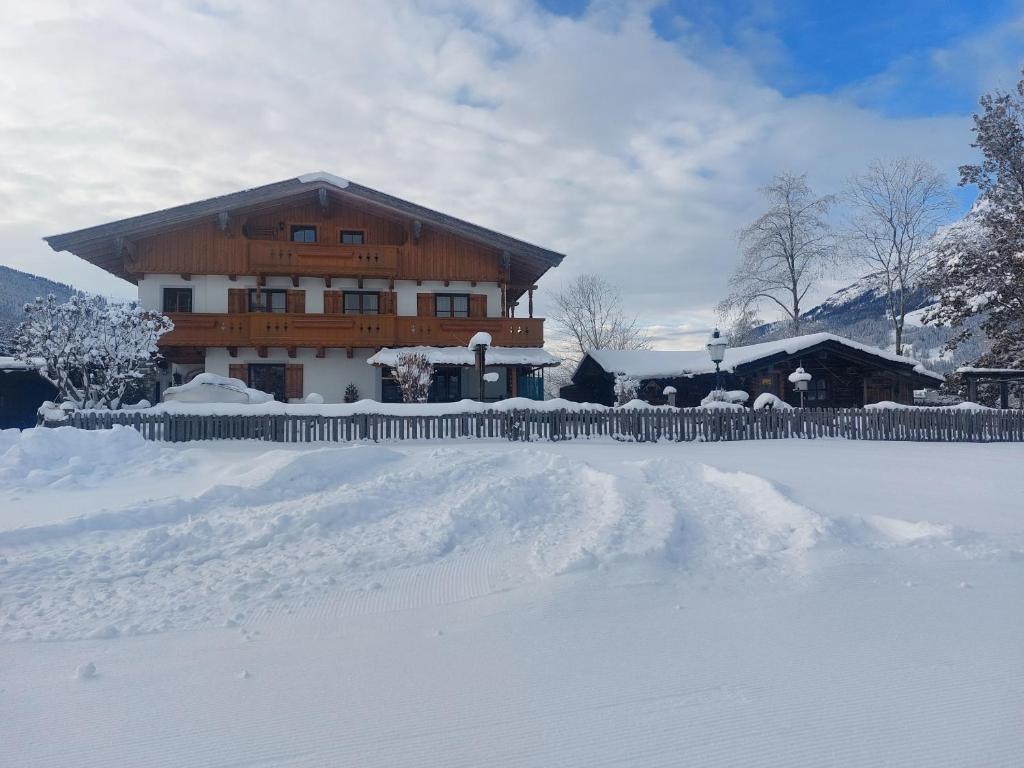ein großes Holzhaus mit Schnee davor in der Unterkunft Ferienhaus Scheiber in Leogang