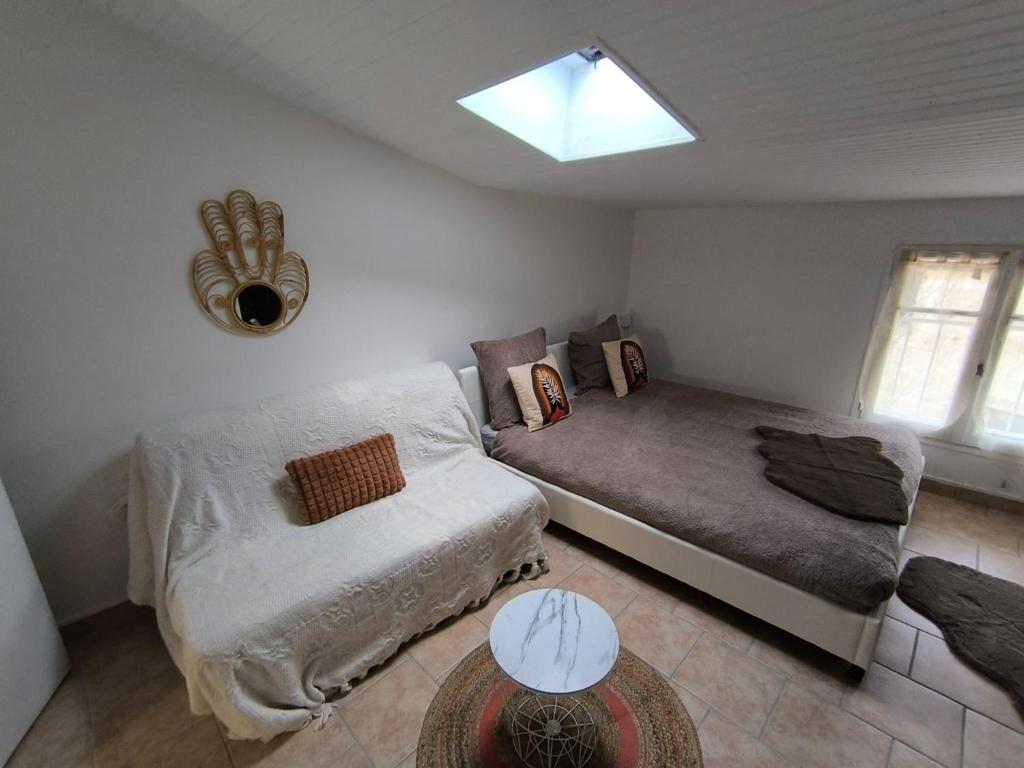 a bedroom with a bed and a couch and a window at L'horizon De Coursan in Coursan