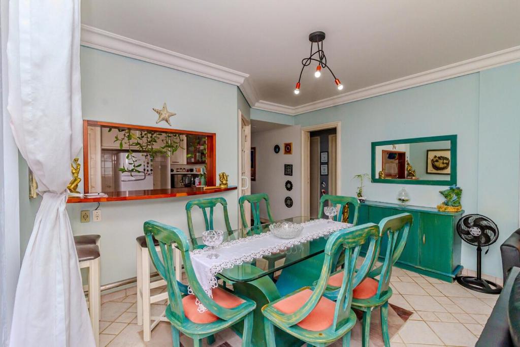 バーハ・ヴェーリャにあるBeira mar pé na areia Barra Velha com Piscinaのテーブルと緑の椅子のあるダイニングルーム