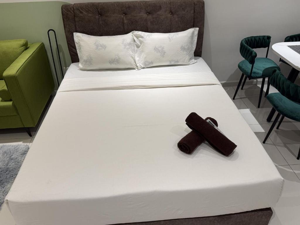 a white bed with a brown cross on it at Majestic Residance Luxury Suites By klcc in Gua Sai
