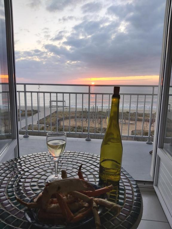 einen Tisch mit einem Glas Wein und einer Flasche in der Unterkunft Les flots bleus face à la mer in Notre-Dame-de-Monts