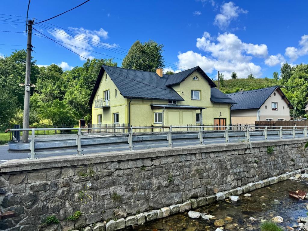 una casa amarilla en un puente sobre un río en Chata Vápenná, en Jeseník