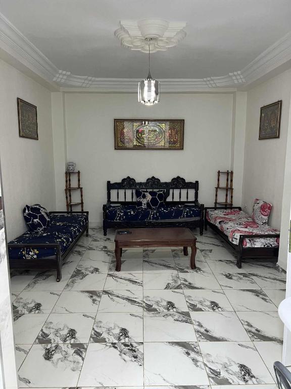 een woonkamer met 3 bedden en een tafel bij Villa ziari in Skikda
