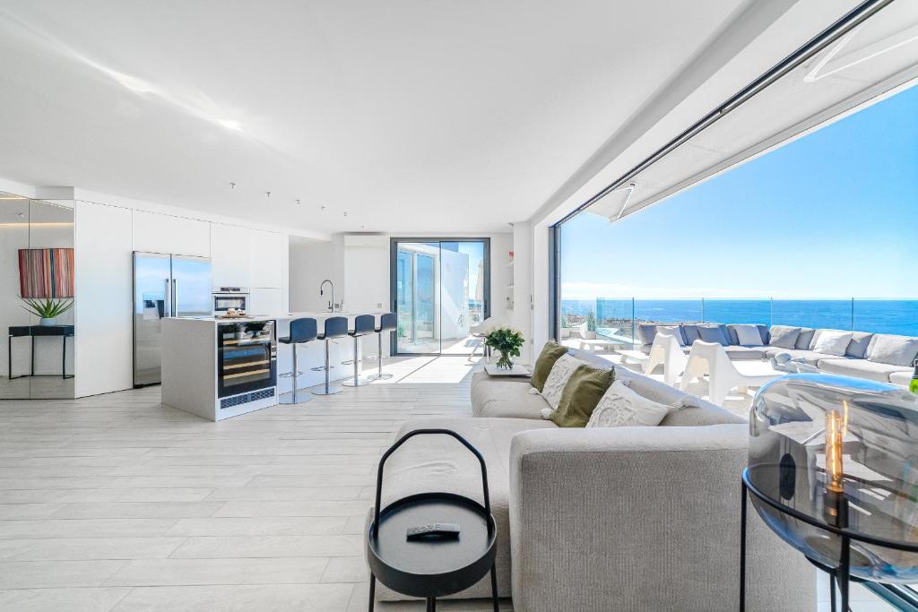 Una sala de estar con un sofá y sillas y una cocina. en White Haven, en Adeje