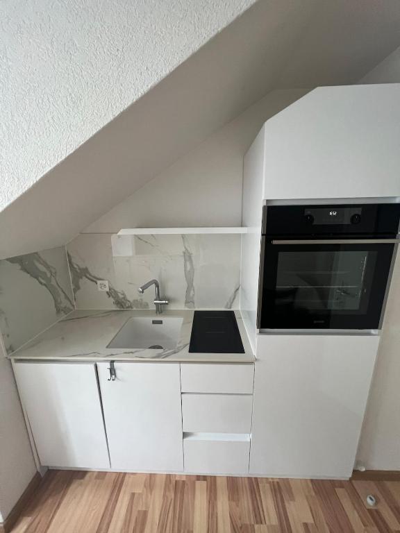 a white kitchen with a sink and a microwave at Joli appartement de 3 pièces in Saint-Imier
