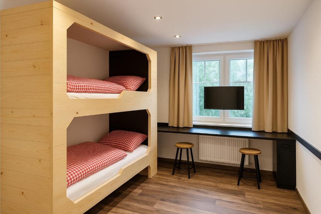 two bunk beds in a room with a desk at TinyAlps in Saalbach Hinterglemm