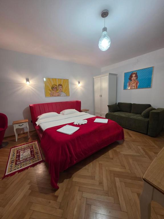 ein Schlafzimmer mit einem roten Bett und einer Couch in der Unterkunft Luky10 in Braşov