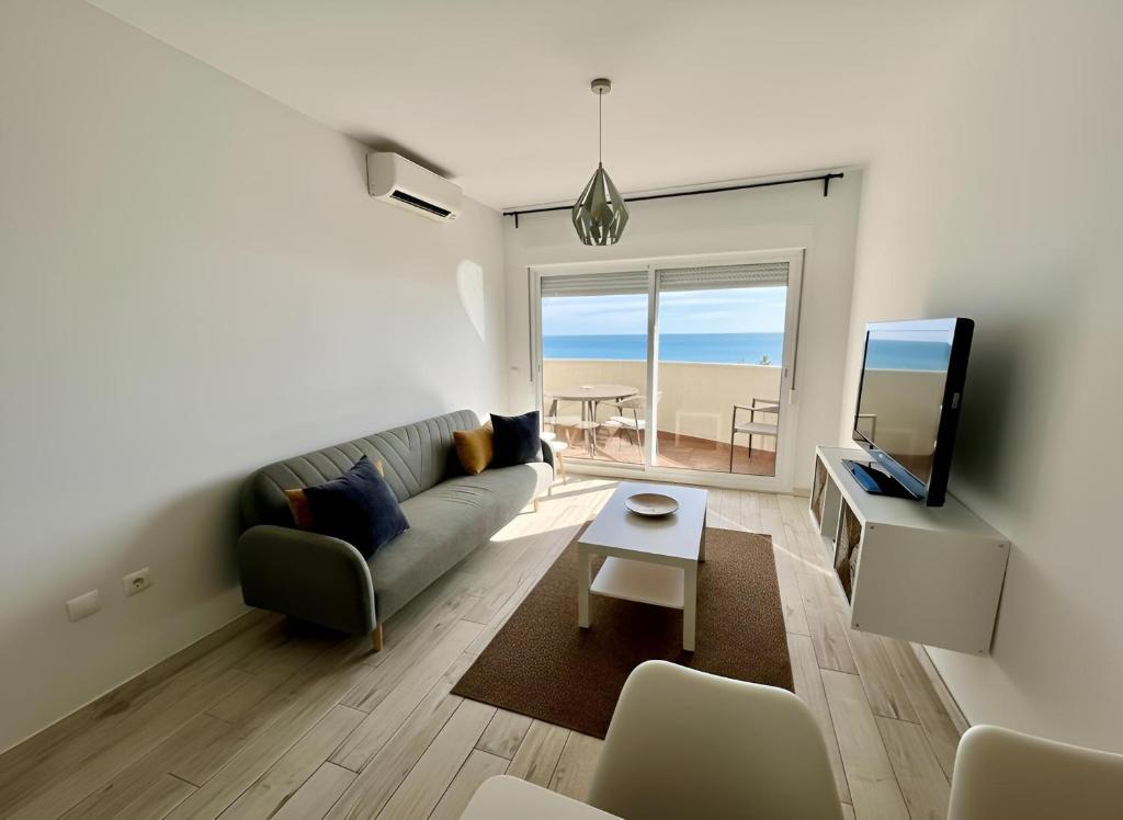 a living room with a couch and a tv and a table at Apartamento Benalbeach in Benalmádena
