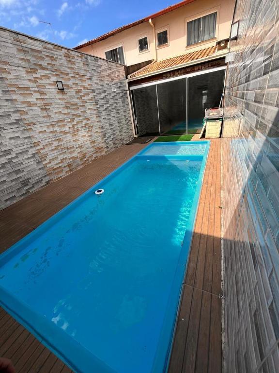 a large blue swimming pool in front of a building at Jacara Beach House - Seu Refúgio in Serra