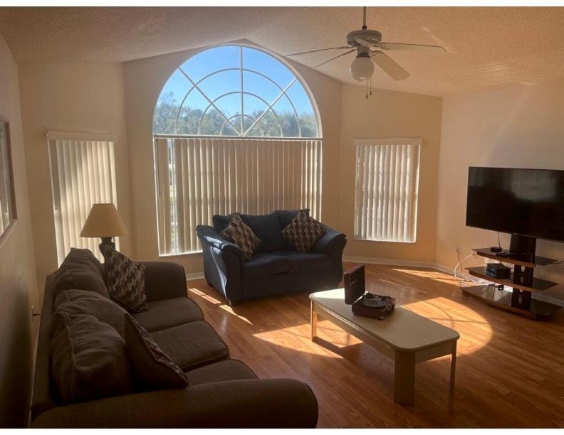 Cozy and Spacious Apartment near Disney Kissimmee في كيسيمي: غرفة معيشة مع أريكة ونافذة كبيرة
