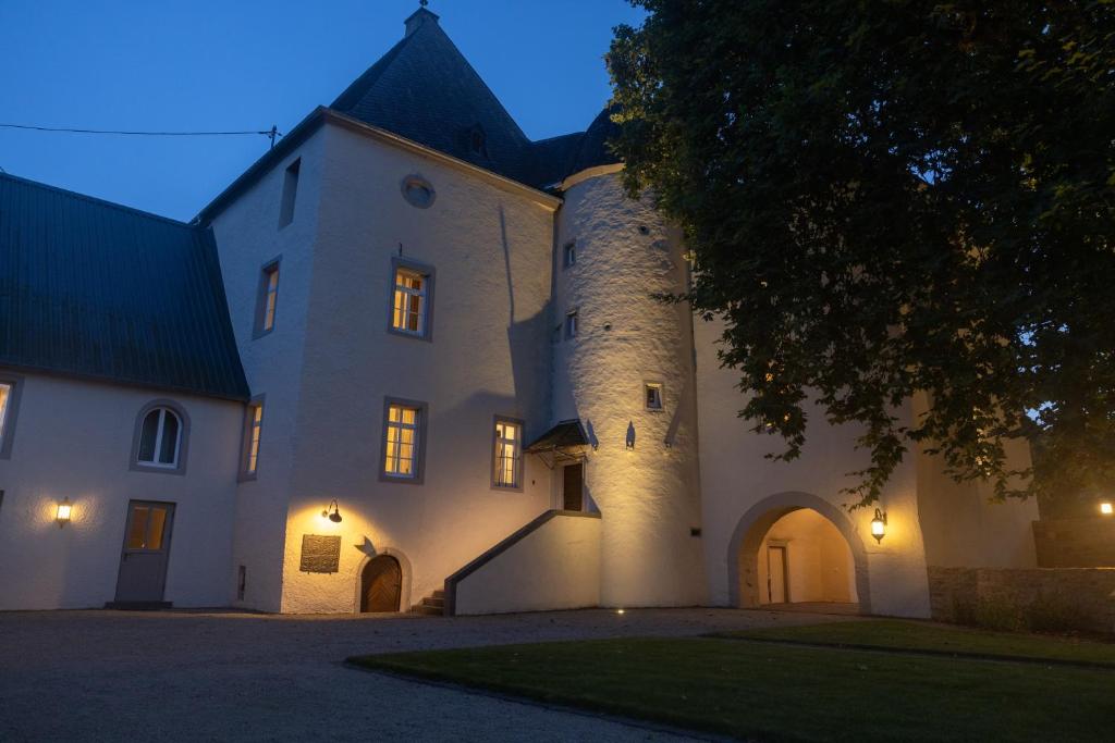 un grand bâtiment blanc avec une tour d'horloge dans l'établissement Charmantes Chateau Lichter - Burghaus, à Ließem