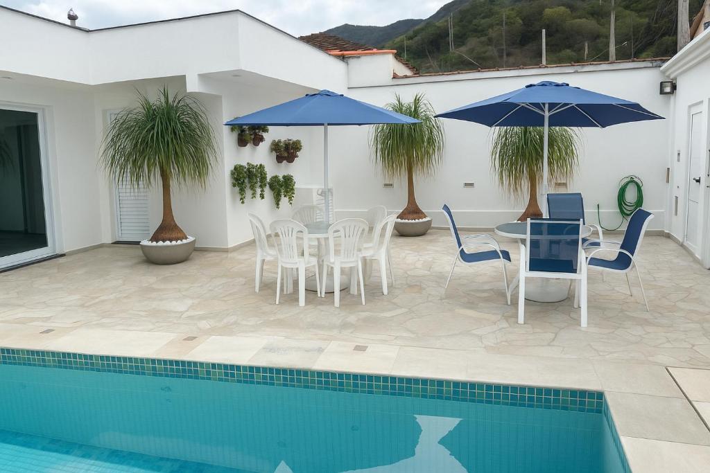 a patio with a table and chairs and a pool at Casa Espaçosa com 5 Quartos Piscina Privativa 300m da Praia Ar condicionado em todos cômodos in São Sebastião