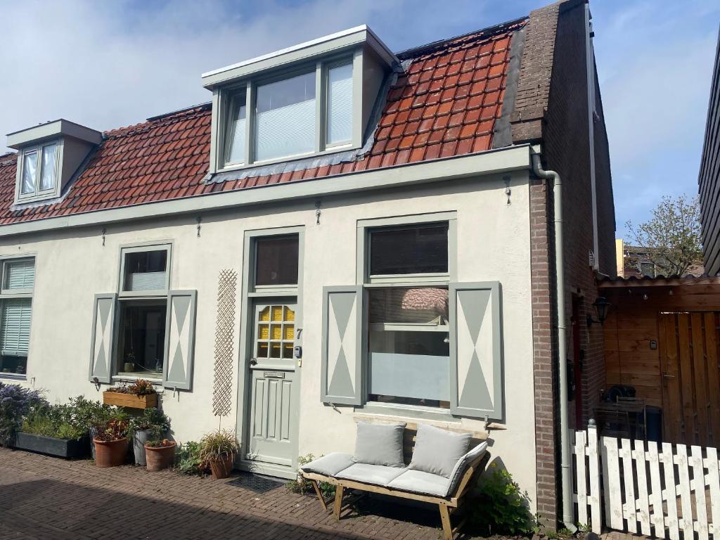ein weißes Haus mit einer Bank davor in der Unterkunft Cosy beach cottage in Zandvoort