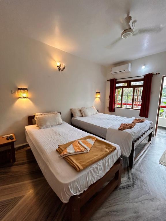 a bedroom with two beds and a window at Maria Paulo Guest House Bar and Restaurant in Agonda