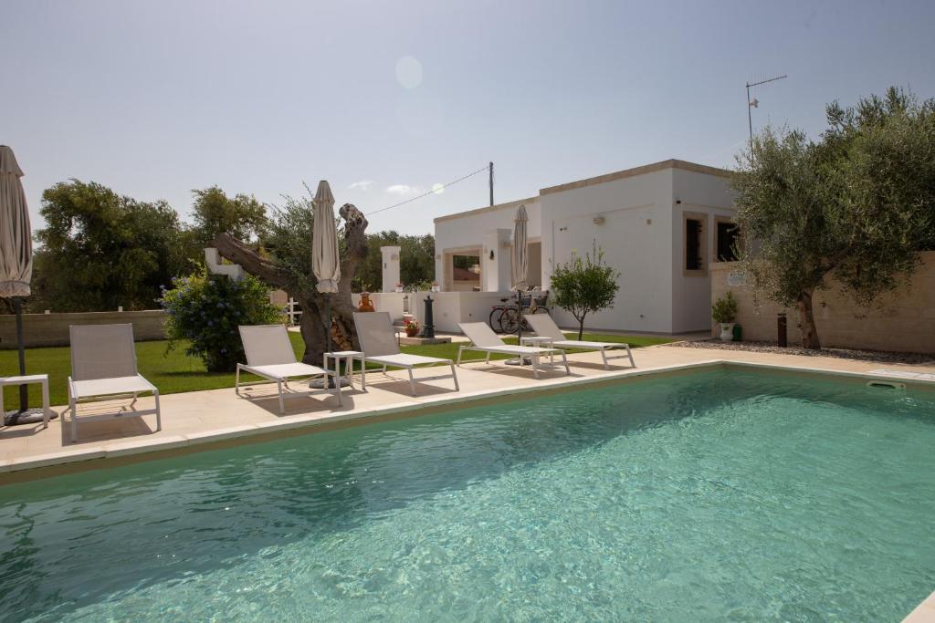 a swimming pool with chairs and a house at Terra Mater - Exclusive Cottage - in Ostuni